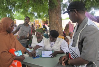 Mulher refugiada confere lista para receber ajuda humanitária | IKMR