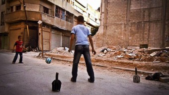 Crianças usam pedaços de morteiros, supostamente disparados por tropas do regime sírio, como goleiras para jogar futebol - Lens Young Homsi‎