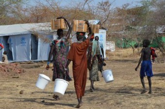 Refugiados do Sudão do Sul que fugiram para a Etiópia após conflitos étnicos internos, que surgiram em sua terra-natal em dezembro de 2013, carregam itens essenciais de ajuda de volta às suas tendas no acampamento Kule.