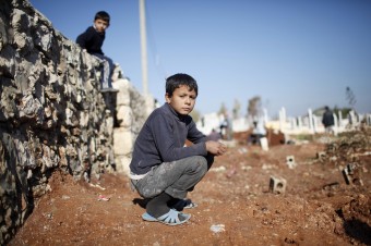 A child watches men dig graves for future casualties of Syria's civil conflict at Sheikh Saeed cemetery in Azaz city