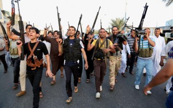 Combatentes iraquianos xiitas seguram suas armas enquanto gritam palavras de ordem contra o Estado Islâmico do Iraque e do Levante em Cidade Sadr, Bagdá (13/6). Foto: AP