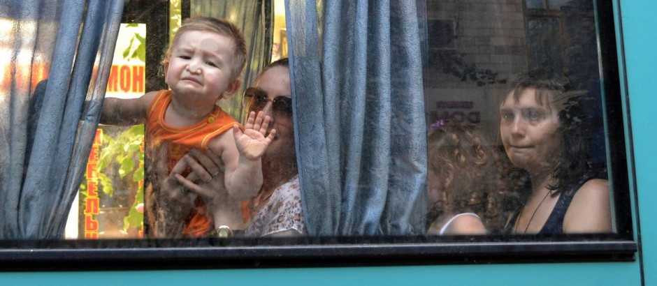Na janela de um microônibus, as expressões tensas de mães e filhos em fuga do Leste da Ucrânia - AP / Andrey Petrov 