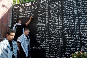 Jovem palestino anota nome de criança morta durante conflito entre forças israelenses e do Hamas. Lista foi feita no campo de refugiados Aida (Foto: Musa Al Shaer/AFP)