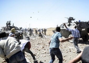 Curdos atiram pedras contra soldados da Turquia após autoridades do país fecharem temporariamente a fronteira com a Síria perto de Suruc, no sudeste da Turquia (Foto: Bulent Kilic/AFP)