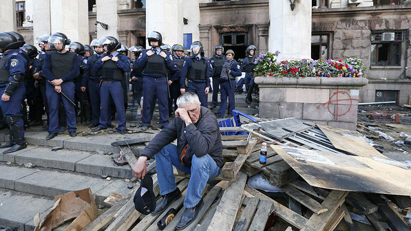Homem é observado por membros das forças de segurança durante um comício fora do edifício sindical ucraniano que pegou fogo ontem (2) em Odessa, na Ucrânia - Gleb Garanich/Reuters